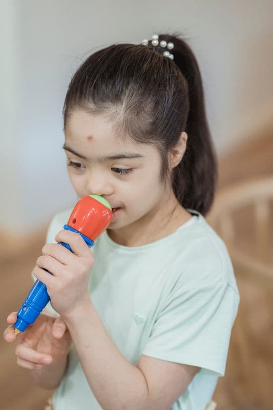 Criança sorridente segurando um microfone de brinquedo durante uma atividade de fala.